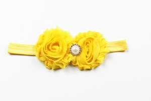 Gros plan du bandeau bébé en mousseline jaune avec boucle en perle et strass