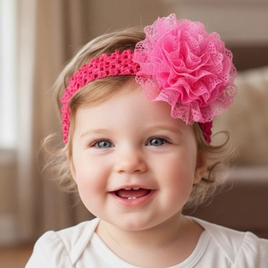 Nahaufnahme eines Babys mit rosa Häkelstirnband und einer großen mehrlagigen Spitzenblume