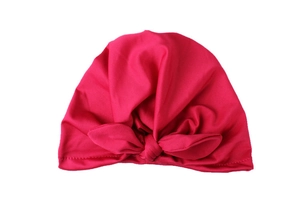 Detailed close-up of rose red baby knot hat with soft knitted fabric and bow decoration