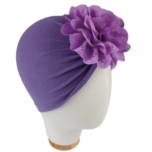Détail d'un turban violet pour bébé avec fleur ajourée et tissu en maille plissé