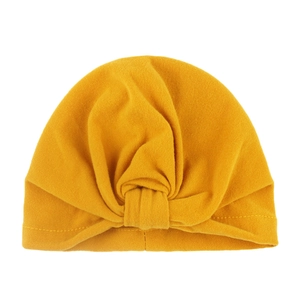 Detail of soft ginger yellow baby turban hat with Bohemian style knot and pleated fabric