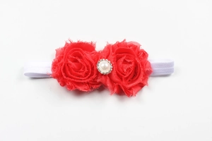 Détail de fleurs en mousseline rouge avec perle et cristaux sur un bandeau blanc bébé