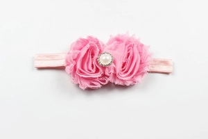 Détail du bandeau bébé avec fleurs en mousseline rose, perle et strass brillants