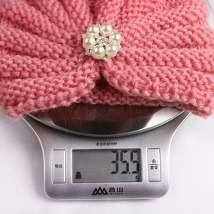 Pink knitted baby headband with pearl and rhinestone flower brooch weighing 35.5g