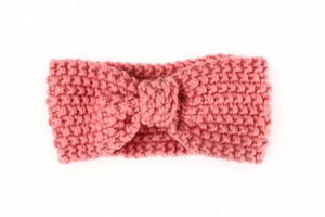 Close-up of pink knitted baby headband with a bow knot design and warm cable knit texture