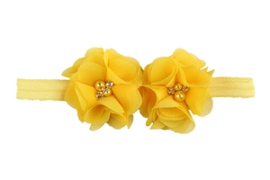 Détail d'un bandeau jaune pour bébé avec fleurs en mousseline, perles et petits strass