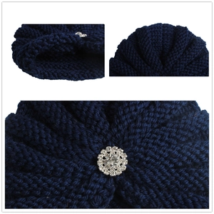 Bonnet en grosse maille bleu foncé pour bébé avec une broche fleurie en strass brillants