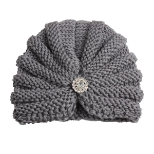 Détail macro du bonnet tricoté gris pour bébé avec motif en V et broche en strass