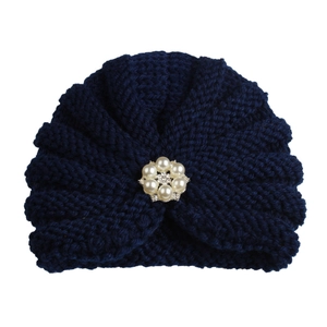 Detailed texture of navy blue knit beanie with a central pearl and rhinestone floral brooch
