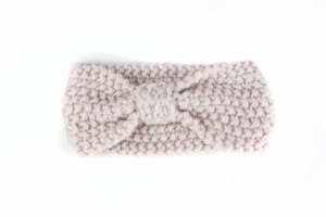 Detailed close-up showing the soft beige knitted texture and bow design of the baby headband