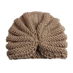 Close-up detail of khaki knitted baby turban hat with soft ribbed texture and center knot