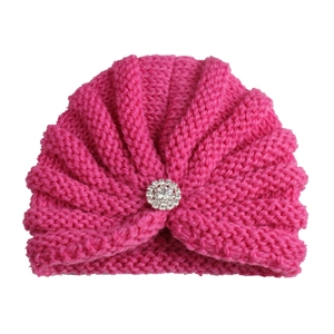 Détail du bonnet en tricot rose pour bébé avec une broche fleur en strass étincelante