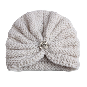 Gros plan du bonnet tricoté crème pour bébé avec boucle en strass et texture nervurée