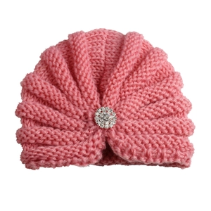 Texture détaillée du bonnet en tricot rose pour bébé avec décoration centrale en strass