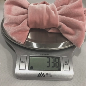 Bandeau bébé en velours rose avec nœud pesant 33,8 g sur une balance de cuisine