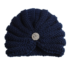 Détail du bonnet turban tricoté bleu marine pour bébé avec une fleur en strass brillant