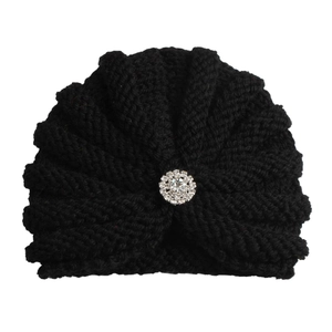 Gros plan d'un bonnet en tricot noir orné d'une broche étincelante en strass de cristal