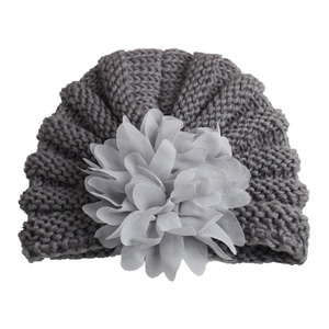 Gros plan du bonnet turban tricoté pour bébé gris avec fleur en mousseline fine