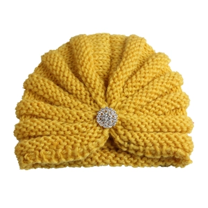 Détail d'un bonnet turban jaune vif pour bébé avec une broche en strass brillante