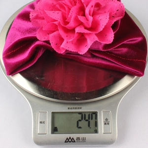 Détail montrant le turban pour bébé en velours rose de 24,7g avec une grande fleur dentelle