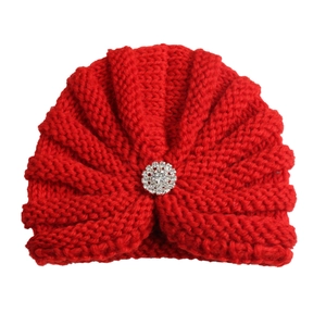Gros plan du bonnet turban rouge pour bébé avec une fleur en strass scintillante