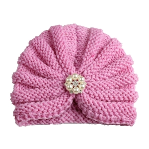 Detail of pink knitted infant turban hat with a centered pearl and rhinestone flower