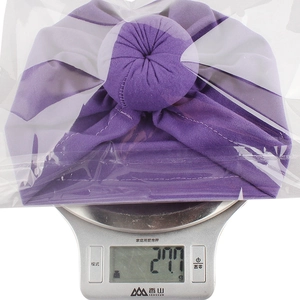 Detail shot showing a 27.7g lightweight purple pleated baby turban on a digital scale