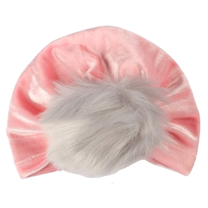 Dettaglio del cappello a turbante in velluto rosa con un grande pompon in ecopelliccia