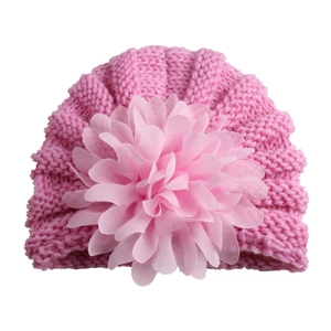 Bonnet en tricot rose pour bébé avec grande décoration florale sur fond blanc pur