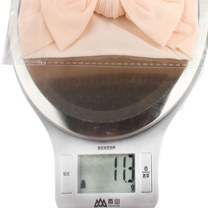 Close-up of lightweight pale pink bow headband on a scale weighing exactly 11.3 grams