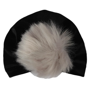 Dettaglio di un cappello turbante per neonato in velluto nero con grande pompon di pelliccia