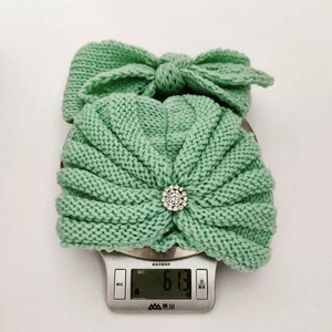 Bandeau nœud tricoté vert menthe avec strass, pesant 61,3g sur une balance