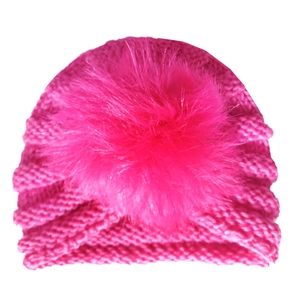 Detail of rose red baby turban hat featuring a fluffy faux fur pom-pom and knit texture