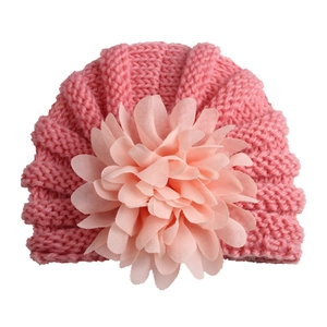 Bonnet bébé rose tricoté en style turban avec une fleur décorative en mousseline