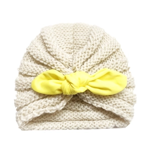 Knitted baby turban hat in cream white featuring a bright yellow fabric bow decoration