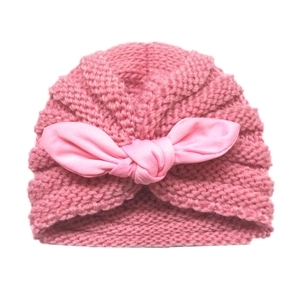 Detailed close-up of knit texture and pink fabric bow on a winter baby turban hat