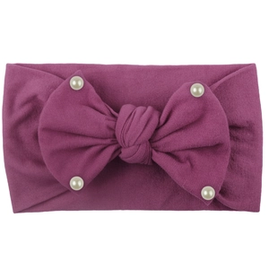 Detail of soft magenta nylon headband with large bow and white pearls for babies