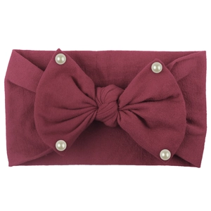Detailed macro view of deep red ribbed knit baby headband with bow and pearls