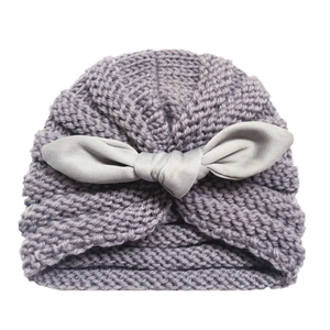 Close-up of lilac knitted baby hat with a light gray bow showing texture and soft fabric