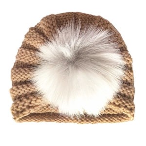 Detail of the chunky knit texture and white faux fur pompom on the warm winter baby hat