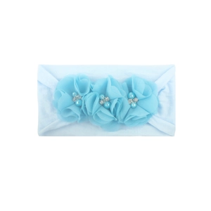 Detalle de diadema celeste para bebé con flores de gasa, perlas de imitación y brillo