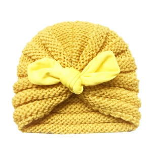 Detailed knit texture of a yellow baby turban hat featuring a large fabric bow accent
