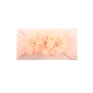 Detalle de diadema rosa para bebé con tres flores de tela y perlas artificiales decorativas