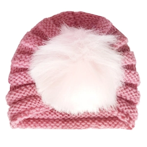 Detail of baby knit turban hat in deep pink featuring a fluffy faux fur pom-pom