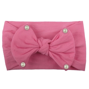 Detail of pink soft nylon baby headband with a large bow and four white pearl accents