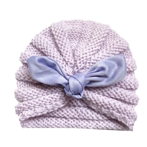 Detail of light purple knitted baby hat featuring a satin bow and thick textured knit fabric