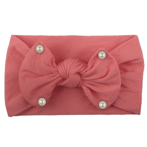 Detail of pink nylon headband with a large bow and white faux pearls for baby girls