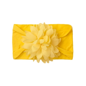 Close-up of bright yellow nylon baby headband with a large chiffon floral decorative flower