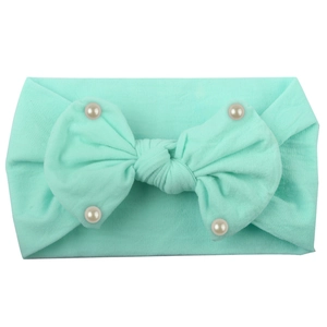 Detail of mint green nylon baby headband with soft texture and pearl-studded bow ornament