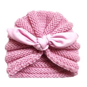 Close-up of pink knit baby turban hat with texture and large fabric bow detail